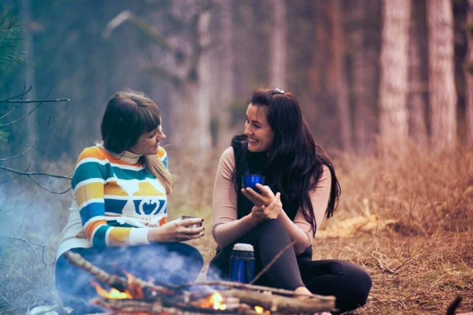 Joyful friendship by a campfire in a serene forest, sharing laughter and warm moments.