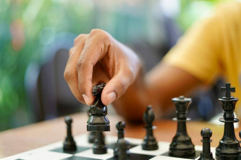 Close-up of a hand moving a black pawn during an intense chess match.