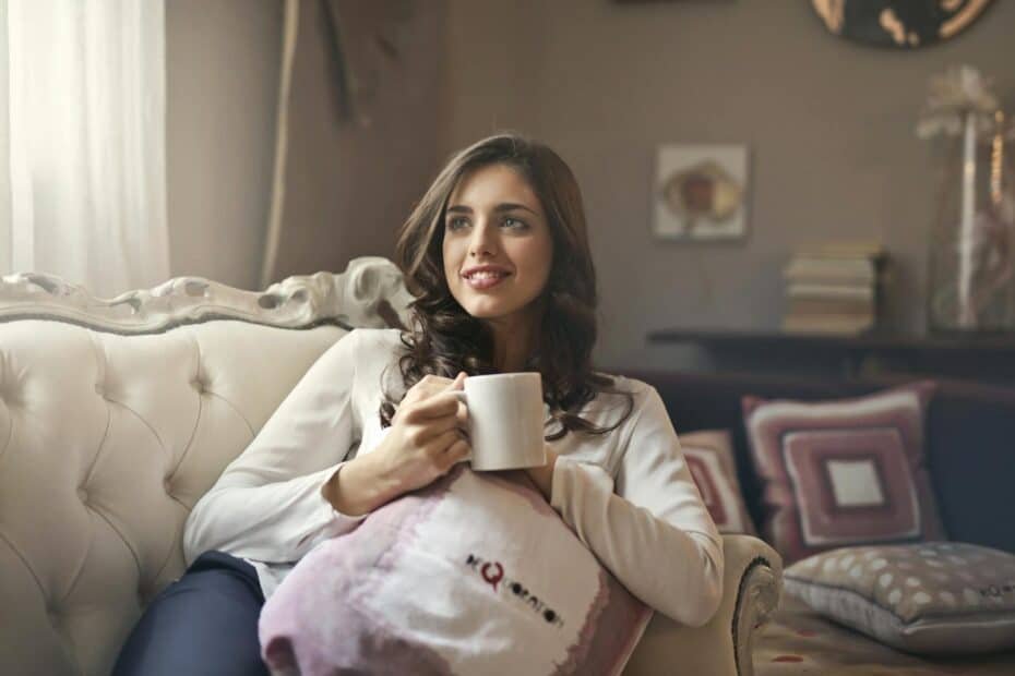 Young woman enjoys a peaceful moment with coffee in a cozy, stylish living room.