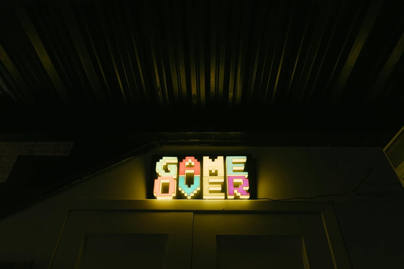 Colorful pixelated game over sign evokes retro arcade nostalgia in a dimly lit setting.