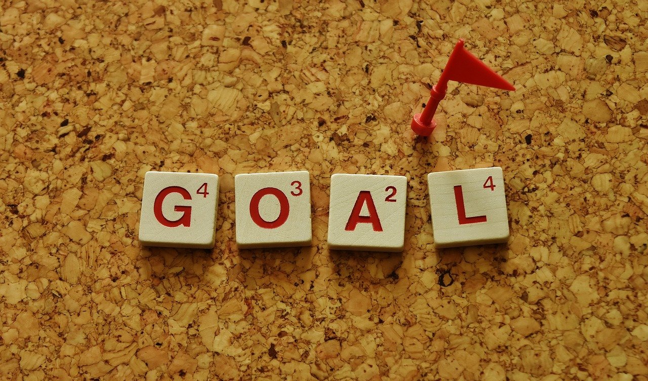 Motivational goal letters on corkboard with playful flag symbolizing achievement and progress.