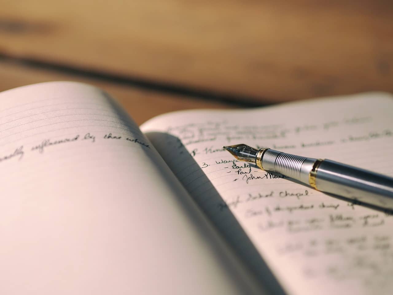 Elegant journaling scene with a fountain pen and handwritten notes on a wooden surface.