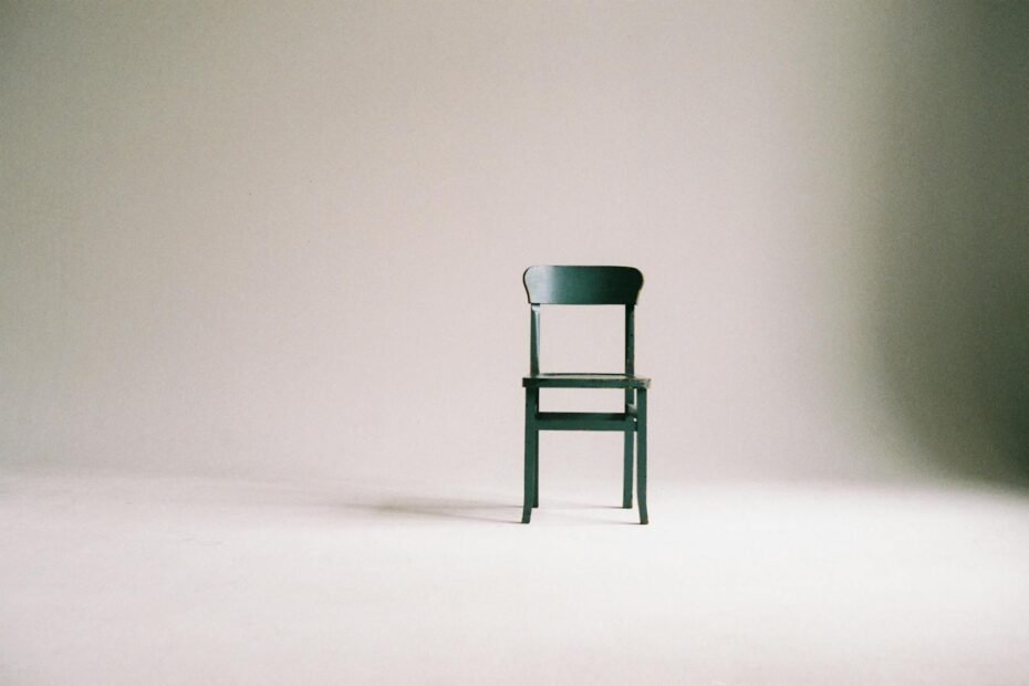 Elegant green chair in minimalist setting invites reflection and tranquility in simple design.