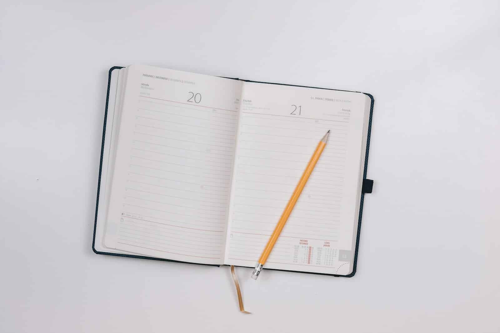 Open black notebook with blank pages and a pencil, inviting creativity and reflection.