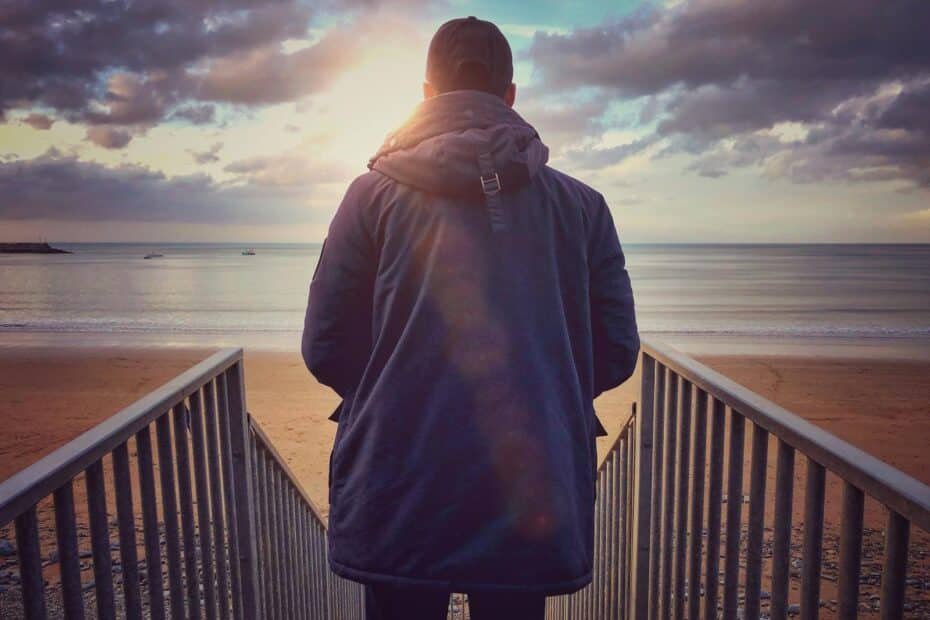 Solitary figure on a beach at sunset, contemplating the horizon in peaceful solitude.