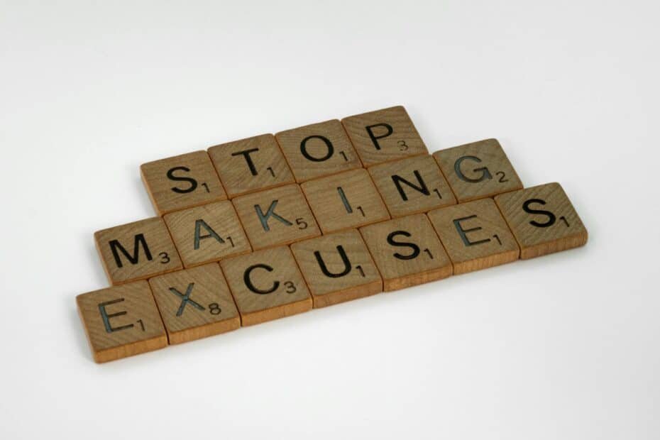 Motivational wooden tiles spelling stop making excuses against a clean white background.