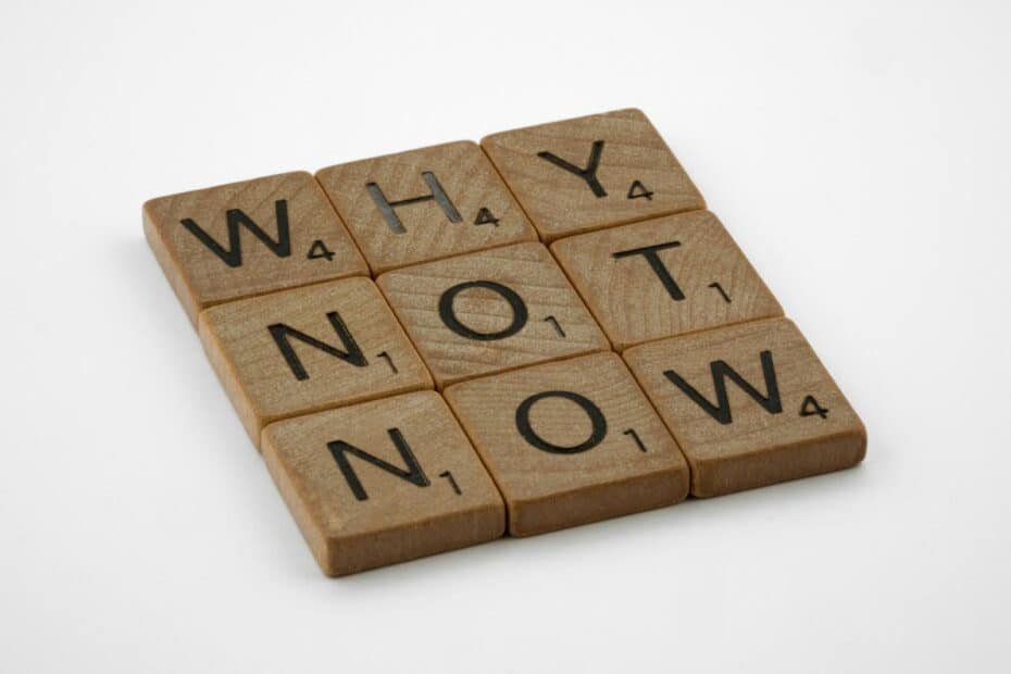 Wooden letter tiles spell why not now, inspiring immediate action and motivation.