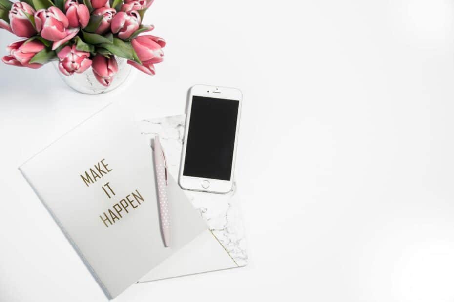 Inspiring minimalist workspace with tulips, a motivational notebook, and silver pen for productivity.