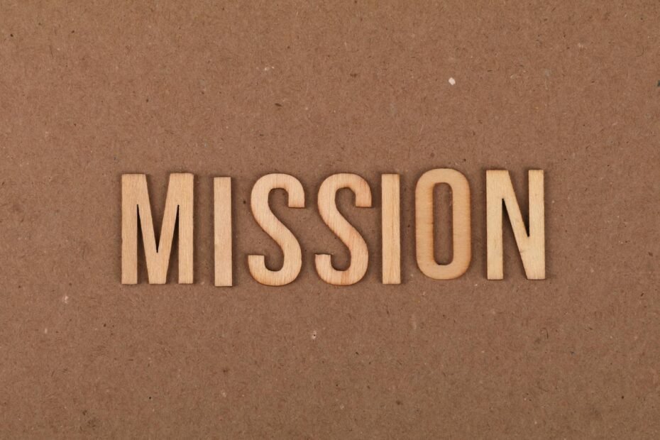 Wooden letters spelling 'mission' on textured cardboard background, emphasizing goals and purpose.