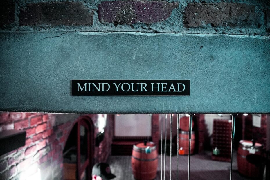 A 'mind your head' sign in a rustic brick barrel cellar setting, creating a safety awareness ambiance.