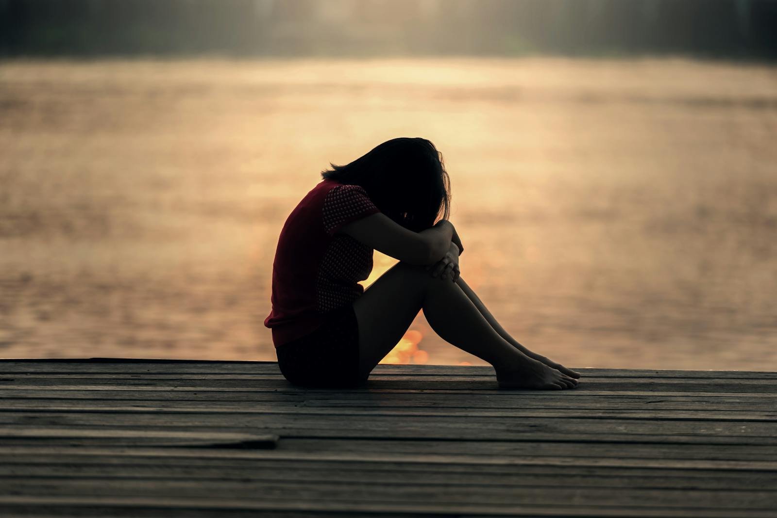 A woman sitting alone on a wooden dock by the lake, showing solitude and reflection. - how do i practice mindfulness  