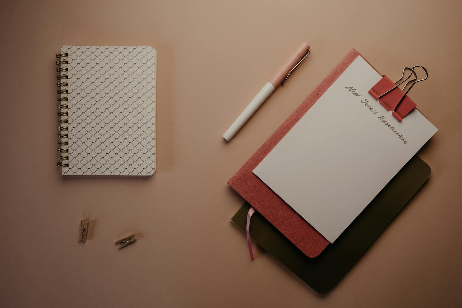 Organized flatlay of notebooks and pen for planning new year's resolutions.