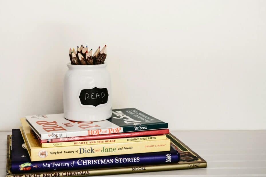 White ceramic pencil organizer on top of stack of books