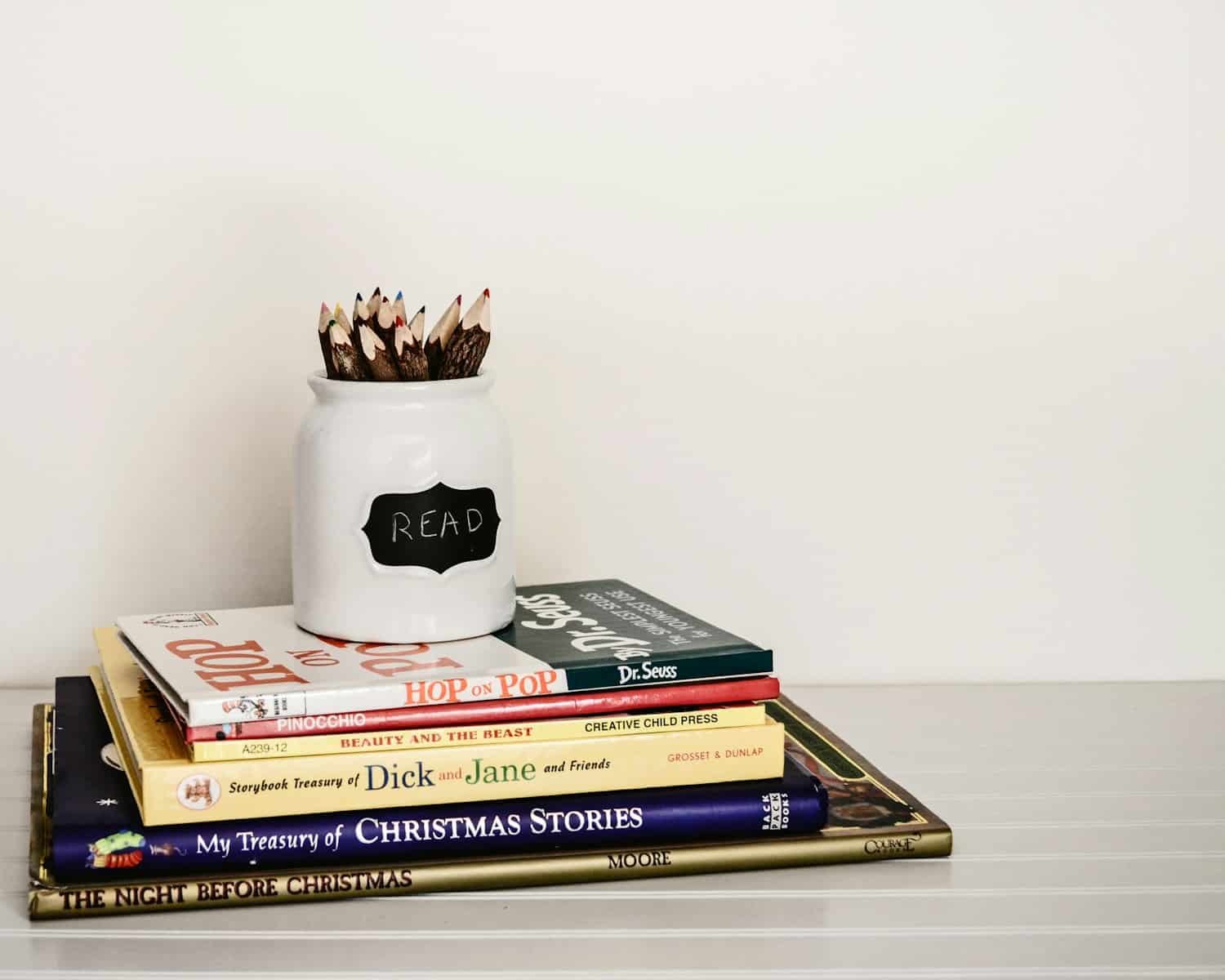 White ceramic pencil organizer on top of stack of books