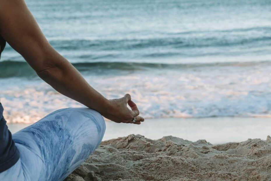 Person in blue shorts sitting on beach shore during daytime