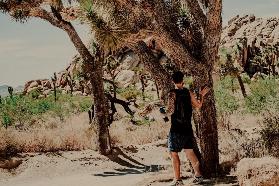 Woman in black t-shirt and blue denim shorts standing on brown sand during daytime