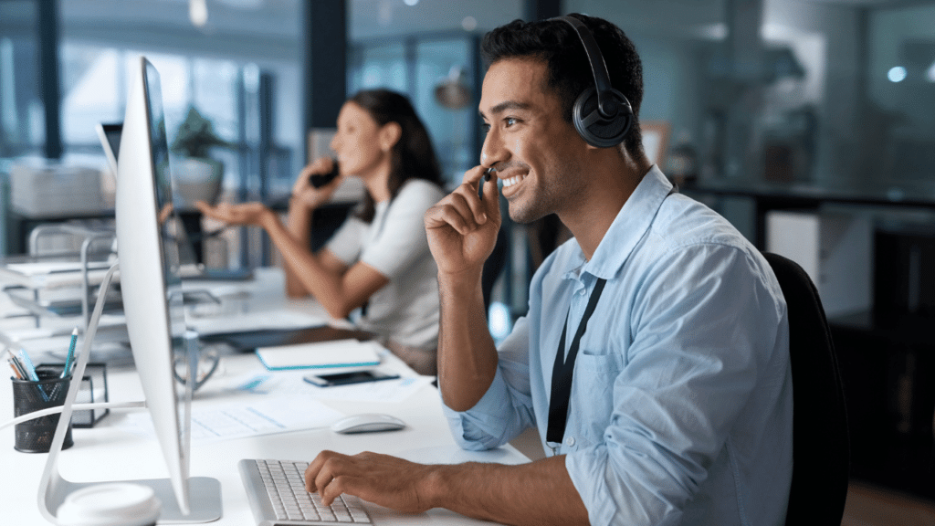 A man wearing headphones and smiling while sitting at a desk