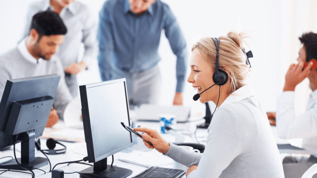 A woman wearing a headset and looking at a computer screen