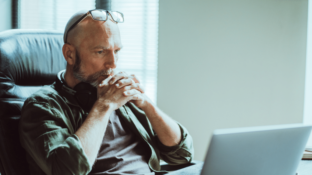 A man with headphones and glasses looking at a laptop