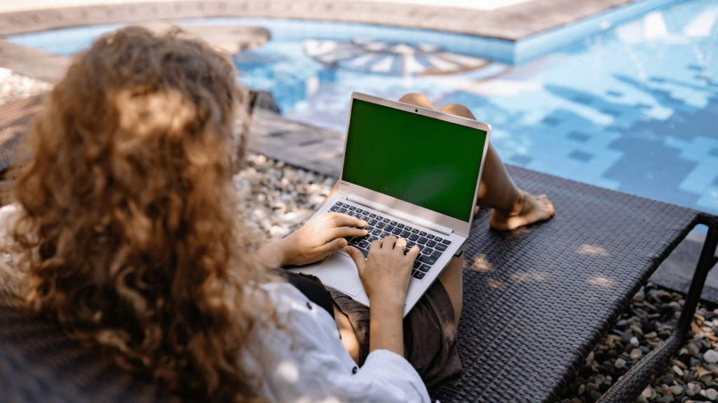 A woman sitting on a deck chair using a laptop