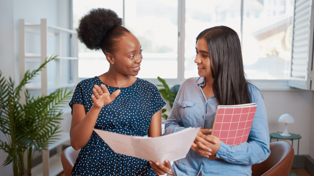 A woman holding a piece of paper and a woman holding a folder