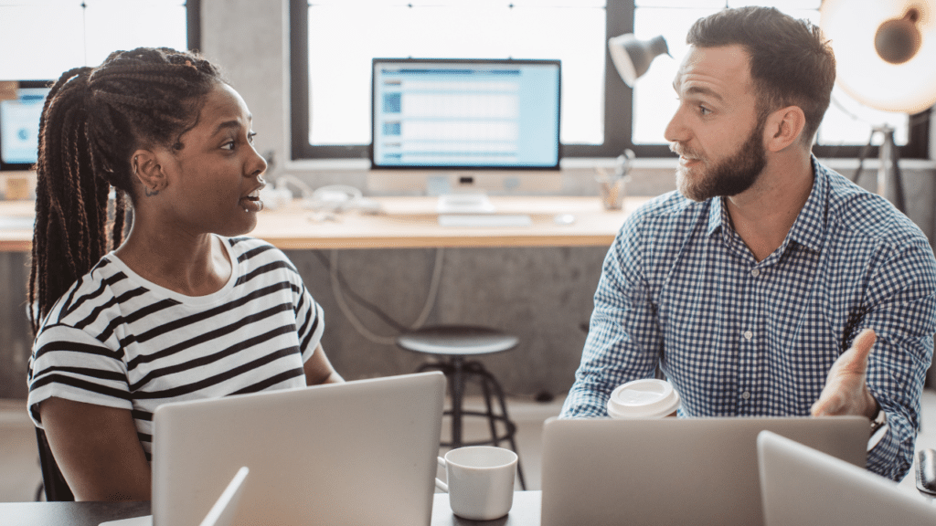 A man and woman sitting at a table with laptops