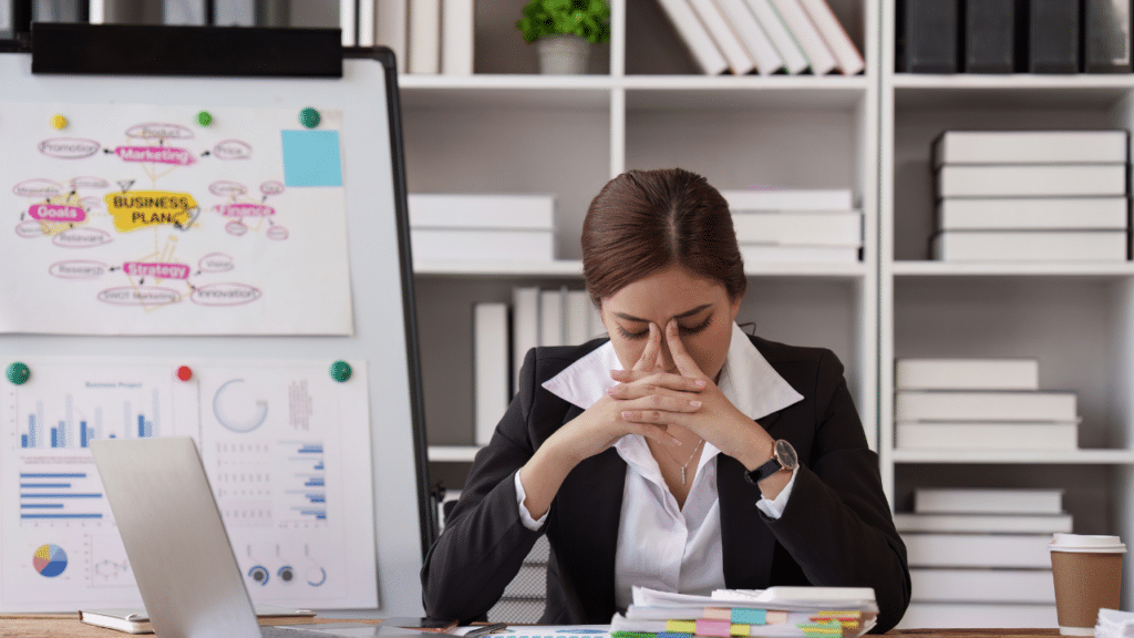 A woman sitting at a desk with her hands on her face