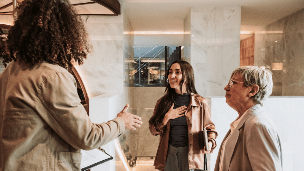 A woman standing in front of a man shaking hands with another woman