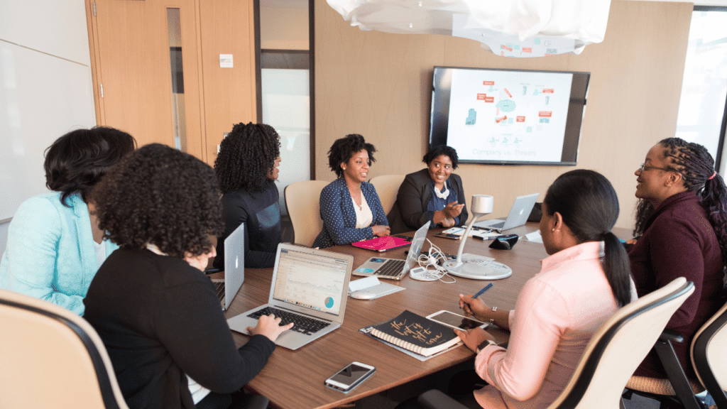 A group of women sitting around a table with laptops