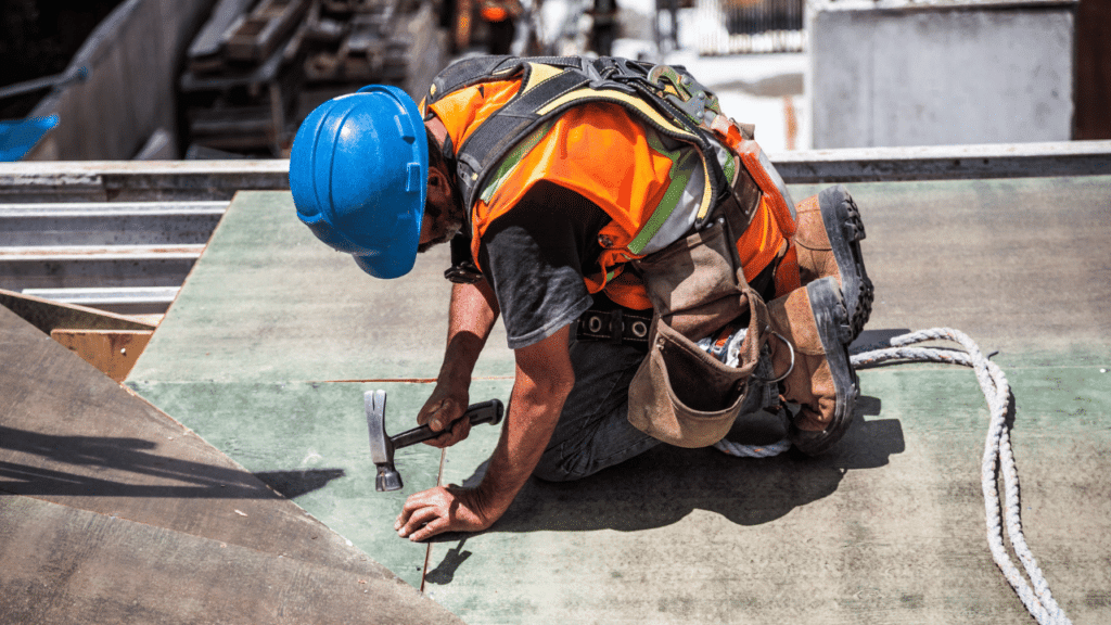 A man in a helmet and vest working on a concrete surface