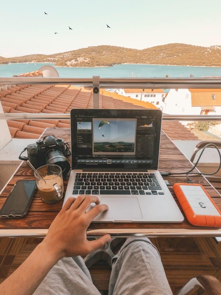 Person holding macbook pro besides orange power bank